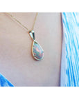 Opal pendant necklace on a person wearing a blue top