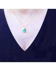 Necklace with a heart-shaped real emerald pendant worn by a person in a navy shirt.