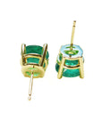 Upside down position of a pair of Muzo Colombian emerald stud earrings on a white background