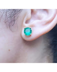 Close-up of an ear wearing a round cut colombian emerald stud earring.