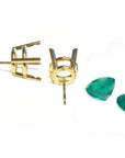 Gold mounting for earrings with loose emerald gemstones aside on a white background