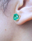 Close-up of an ear wearing a round cut emerald stud earring, to show left ide profile