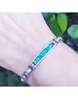 Silver bracelet with vibrant Colombian emeralds and princess-cut diamonds on a wrist.