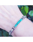 White gold bracelet with vibrant Colombian emeralds and princess-cut diamonds on a wrist.