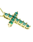A 14k yellow gold cross necklace pendant with natural colombian emeralds on a side profile view.