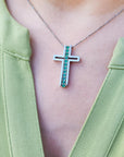 Cross-shaped necklace with genuine colombian emeralds worn by a person in a green top.