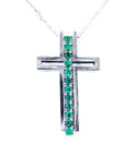 A white gold cross pendant with colombian emeralds on a topside view position.
