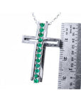 14K white gold cross pendant with 0.50 ct. round Colombian emeralds, shown with a ruler for size.