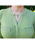 0.50 ct. Colombian emerald cross pendant necklace with round cut emeralds, 14K gold, worn on a woman.