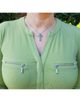 0.50 ct. Colombian emerald cross pendant necklace with round cut emeralds, 14K gold, worn on a woman.