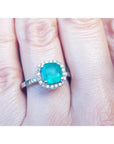 1.71 ct. Colombian emerald cushion-cut halo diamond ring in 14K white gold on a finger.