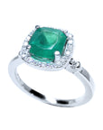 A 14k white gold ring with a cushion cut natural Colombian emerald encircled by a halo diamond on a white background