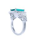 18K white gold ring with a rectangular emerald, diamond halo, and trillion side diamonds.