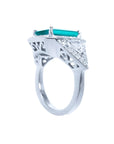18K white gold ring with a rectangular emerald, diamond halo, and trillion side diamonds.