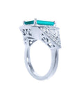 18K white gold ring with a rectangular emerald, diamond halo, and trillion side diamonds.
