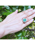 GIA certified 3.98 ct emerald and diamond ring in 18K white gold on a hand.