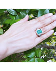 GIA certified 3.98 ct emerald and diamond ring in 18K white gold on a hand.