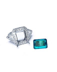 18K white gold diamond halo ring setting with trillion sides next to a loose rectangular emerald.