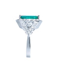 18K white gold ring with a rectangular emerald center stone, surrounded by diamonds and trillion cut sides.