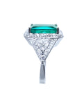18K white gold ring with a rectangular emerald, diamond halo, and trillion side diamonds.