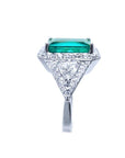 18K white gold ring with a rectangular emerald, diamond halo, and trillion side diamonds.