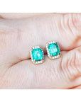 Colombian emerald and diamond halo stud earrings in 14k yellow gold.