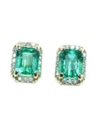 Pair of natural emerald stud earrings halo diamond on a front position, plain top view.