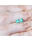 Rectangular Colombian emerald and diamond halo stud earrings in 14k yellow gold.