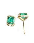 Pair of emerald green gemstone earrings with gold settings on a white background.