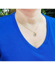 14k yellow gold necklace with a round pendant featuring a natural Colombian emerald and diamond accent.