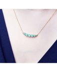14K gold necklace with five round, medium light green Colombian emeralds, graduating in size.