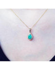 Pear-shaped Colombian emerald pendant with halo diamonds on a 14K yellow gold chain.