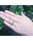 Oval Colombian emerald ring with baguette diamonds set in 14K white gold on a hand.