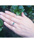 Oval Colombian emerald ring with baguette diamonds set in 14K white gold on a hand.