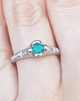A natural oval cut colombian emerald ring in white gold on a finger.