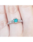A natural oval cut colombian emerald ring in white gold on a finger.