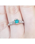 A natural oval cut colombian emerald ring in white gold on a finger.