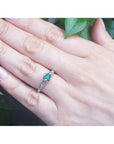 Oval-cut Colombian emerald ring with baguette diamonds in 14K white gold on a hand.
