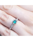 Oval-cut Colombian emerald ring with baguette diamonds in 14K white gold on a hand.