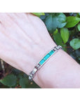 white gold bracelet with vibrant Colombian emeralds and princess cut diamonds on a wrist.