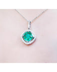 Cushion-cut Colombian emerald pendant with diamond halo on a delicate 14K white gold chain.