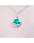 Cushion-cut Colombian emerald pendant with diamond halo on a delicate 14K white gold chain.