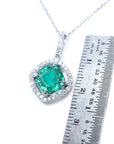 Emerald pendant on a white gold chain with a ruler for scale on a white background.