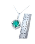 Cushion-cut Colombian emerald pendant with halo diamonds in 14K white gold, next to a ruler.