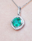 Emerald pendant with diamond accents on a light pink skin background.