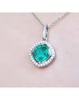 Emerald pendant with diamond accents on a light pink skin background.