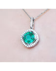 Emerald pendant with diamond accents on a light pink skin background.