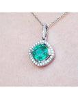 Emerald pendant with diamond accents on a light pink skin background.