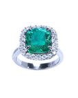 This cushion cut Colombian emerald ring with a halo diamond is positioned at the front, fully displaying the top stone.