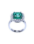 Cushion cut Colombian emerald ring with diamond halo in 18K white gold.
